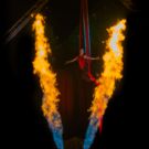 Artistin hängt an einem Vertikaltuch und Flammen schiesen in die Luft