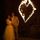 Brautpaar steht vor einem brennendem Herz bei der Hochzeitsfeuershow