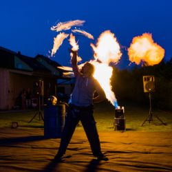 Feuerkuenstler mit Flammenwerfer